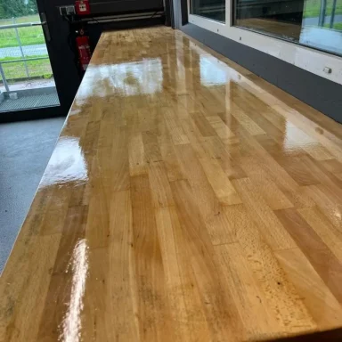 Langer, glänzender Holztisch in einem modernen Raum mit Fenstern.